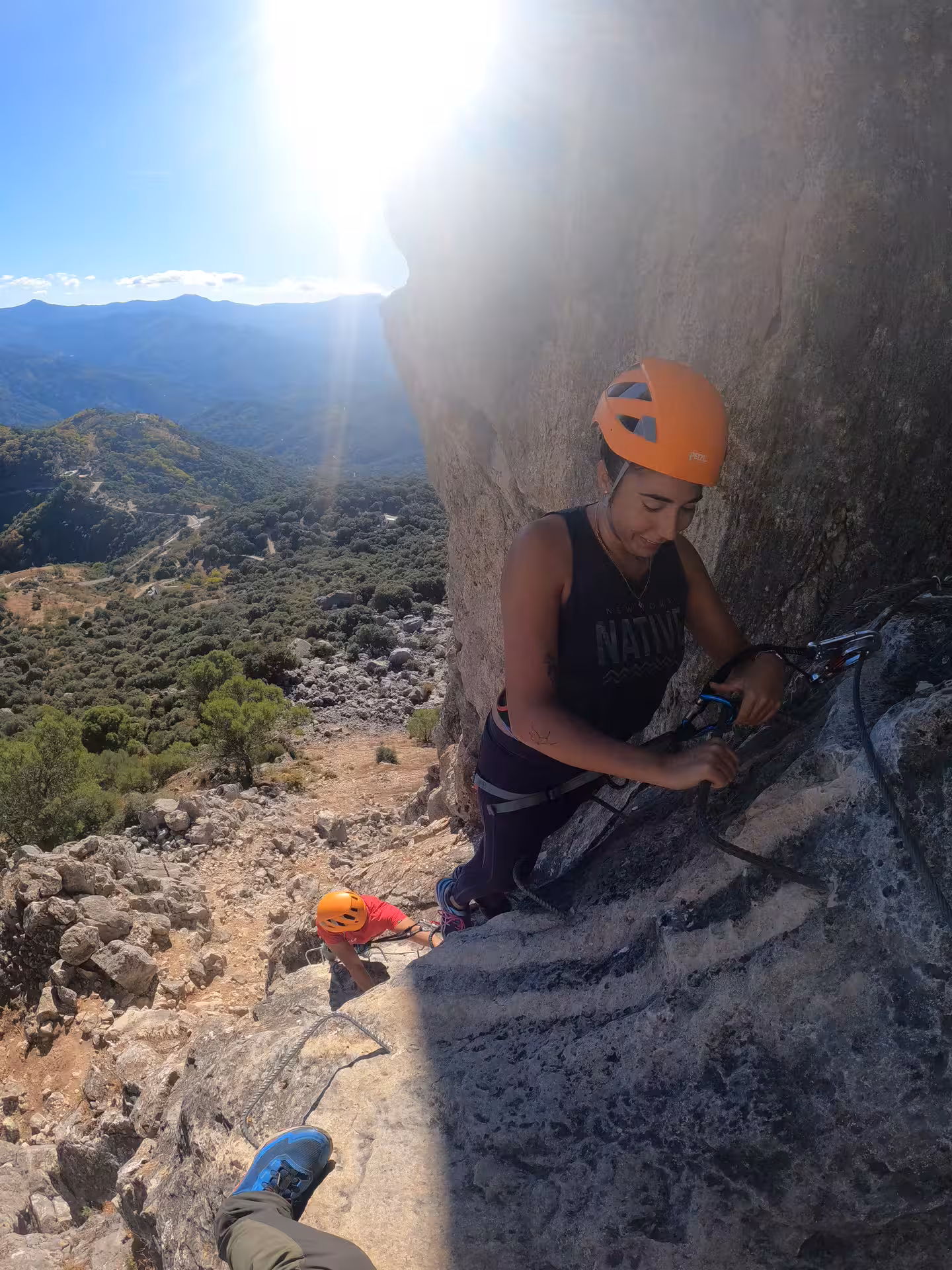 Climbers navigating a steep rock face on Benalauría’s Via Ferrata, with expansive views of Costa del Sol’s lush landscape.