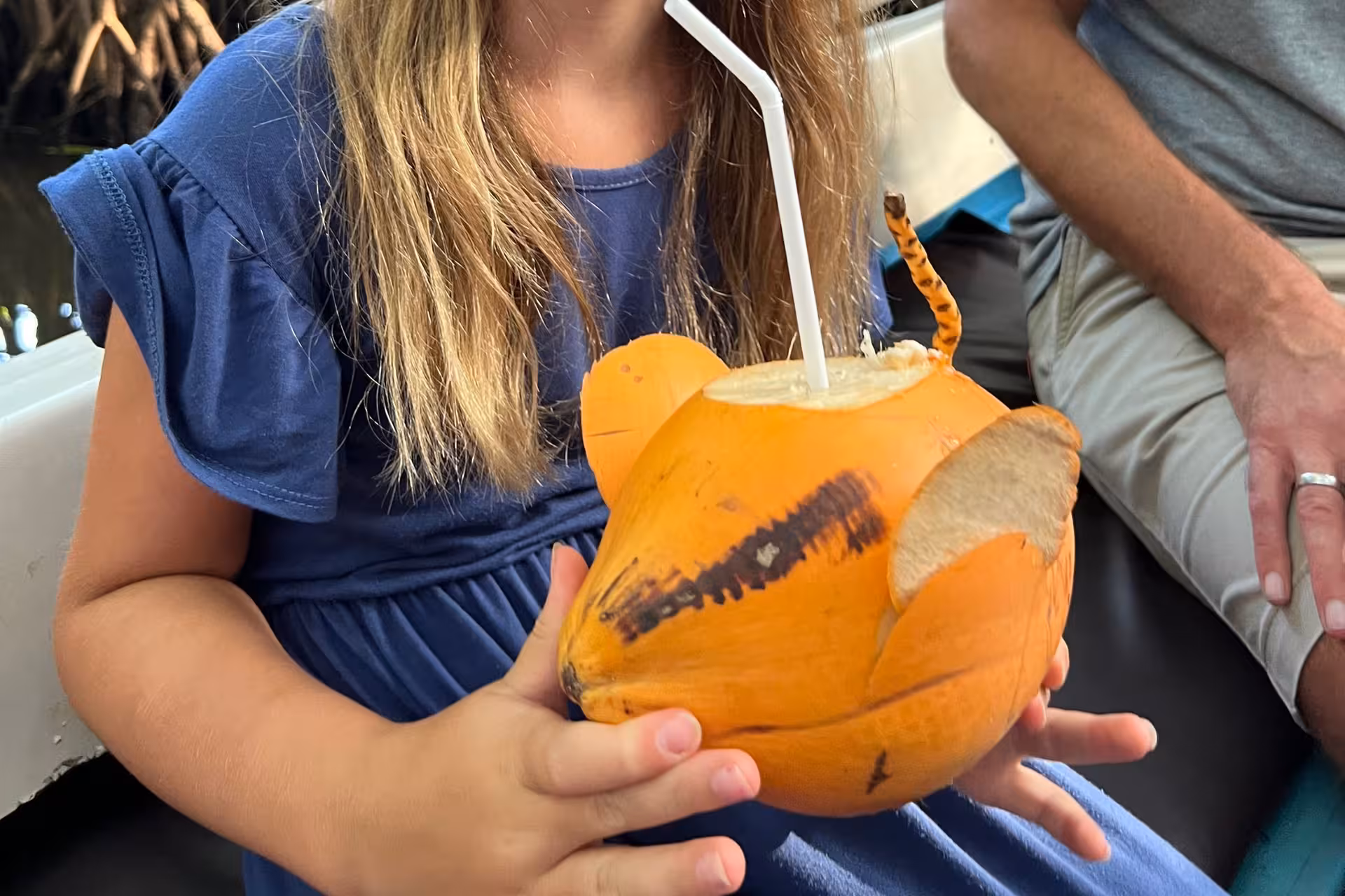 Child holding fresh king coconut drink on Bentota River safari boat, a refreshing Sri Lanka river cruise