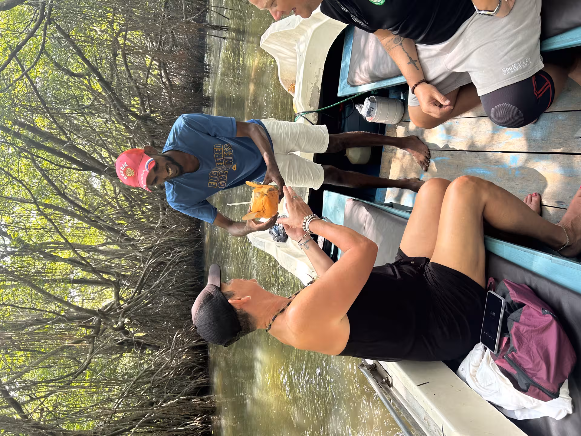 Guide serves fresh king coconut on Bentota River safari boat through lush mangroves in Sri Lanka