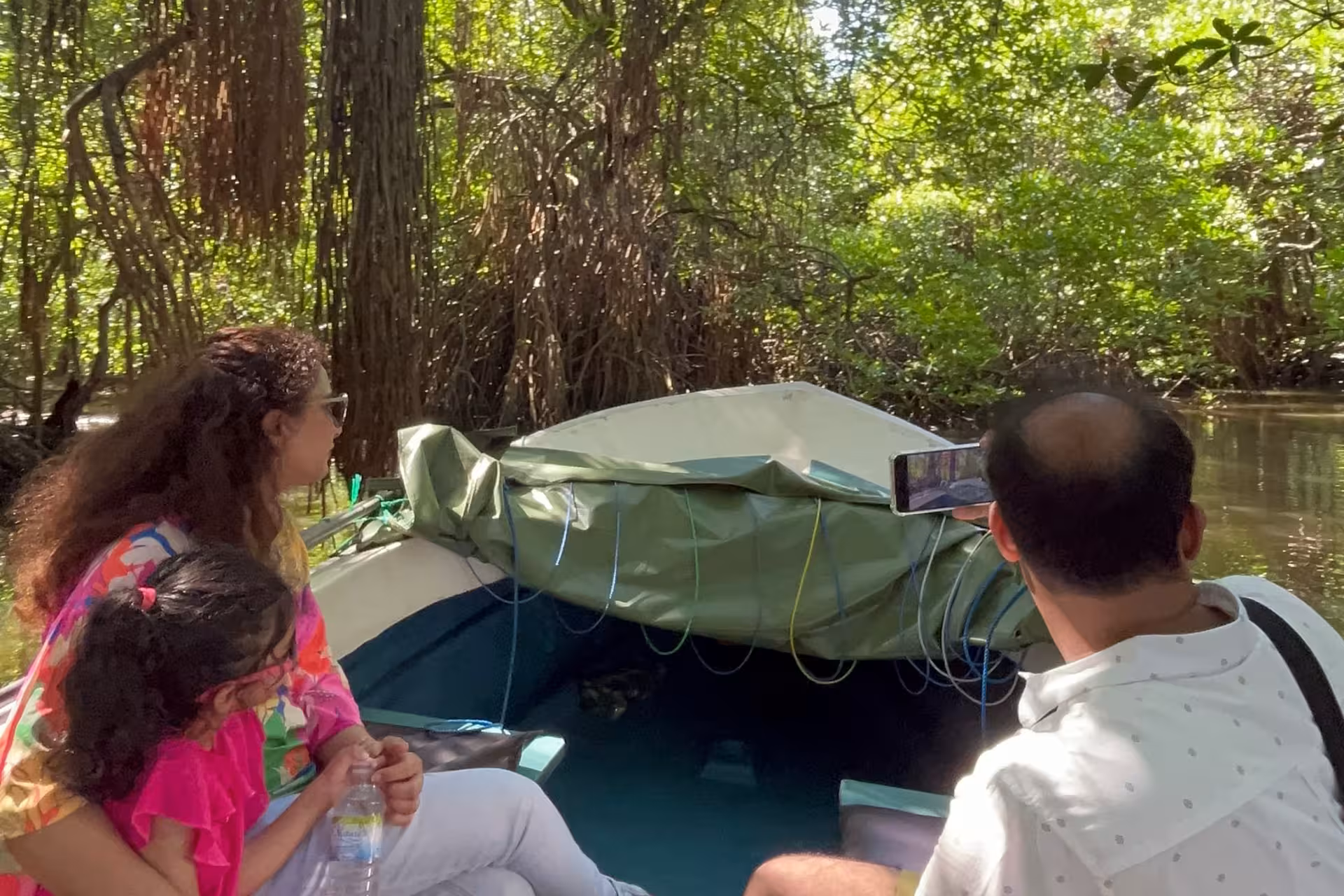 Family enjoying Bentota River safari boat ride through mangrove tunnels, spotting wildlife in Sri Lanka
