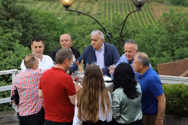 Group of visitors tasting wine at a vineyard with lush greenery during Berat 4x4 off-road tour.