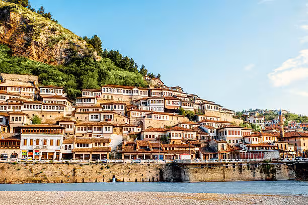 Charming hillside view of Berat, Albania's historical white Ottoman houses near the Osum River under a clear sky.