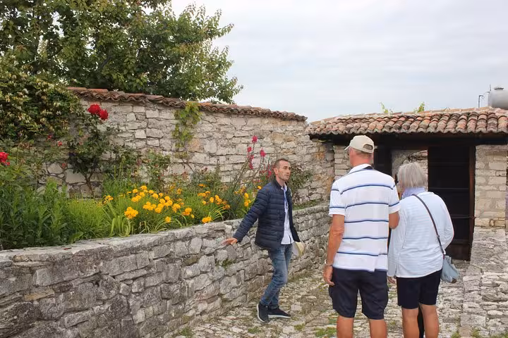Tour guide explaining historical architecture to visitors in a quaint stone courtyard in Berat, Albania.