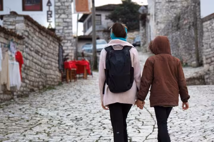 Two tourists stroll down a charming cobblestone street in Berat, capturing the essence of this historic Albanian city.