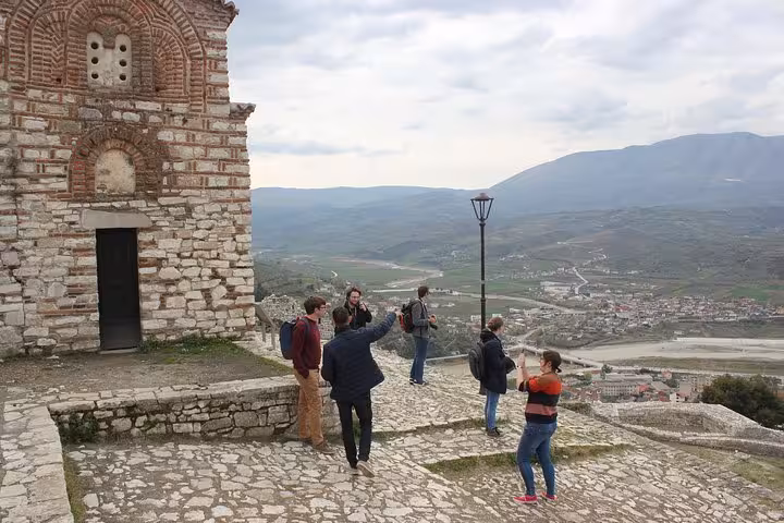 Tour group with expert guides enjoying a scenic view of Berat from a historic site, highlighting the city's rich heritage.