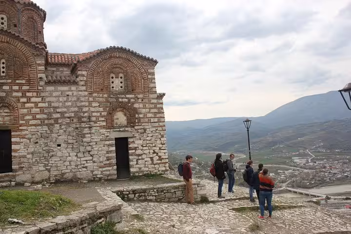 Guided tour group admiring panoramic views of Berat from a historic stone building, emphasizing cultural exploration.