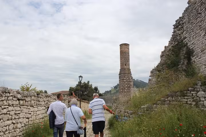 Tourists walk along a historic stone path in Berat, Albania, guided tour featuring ancient architecture and scenic views.