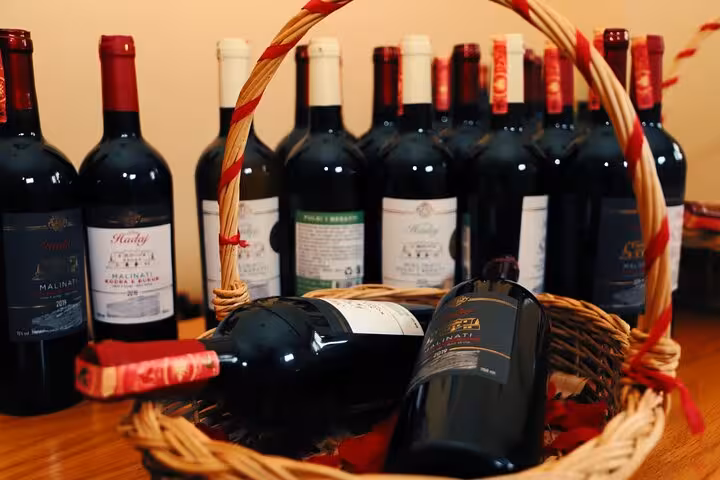 A collection of fine wine bottles elegantly arranged in a wicker basket for vineyard tasting in Berat.