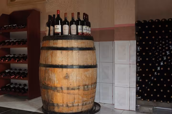 Rustic wine cellar in Berat featuring an oak barrel adorned with local wine bottles, perfect for a classic tasting tour.