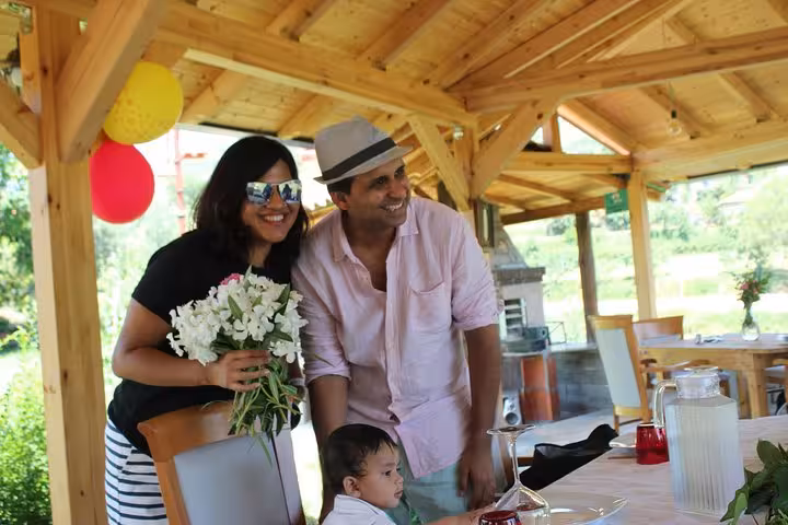 Family smiling and enjoying fresh flowers in a cozy wooden shelter during the Berat wine and food experience.
