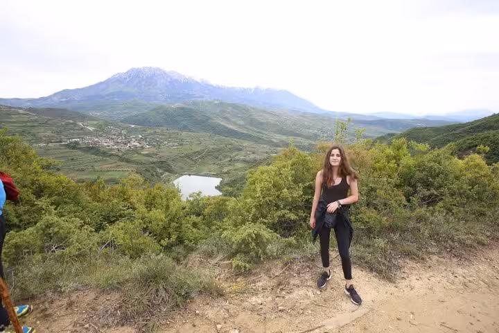 Traveler posing with panoramic view of Berat's lush landscape and mountains during a wine and food tour adventure.