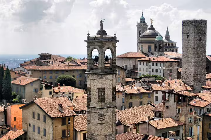 Close-up of Bergamo Alta bell tower, stone rooftops and cathedral domes explored on a 2.5-hour private walking tour in Italy