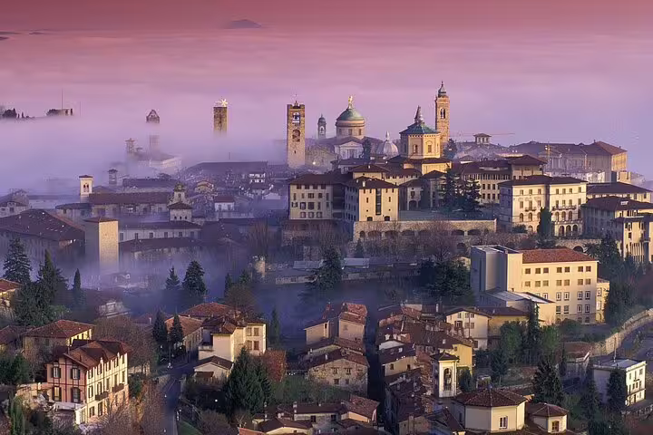 Panoramic sunrise over Bergamo Alta’s medieval skyline and domes, seen on a guided 2.5-hour private walking tour