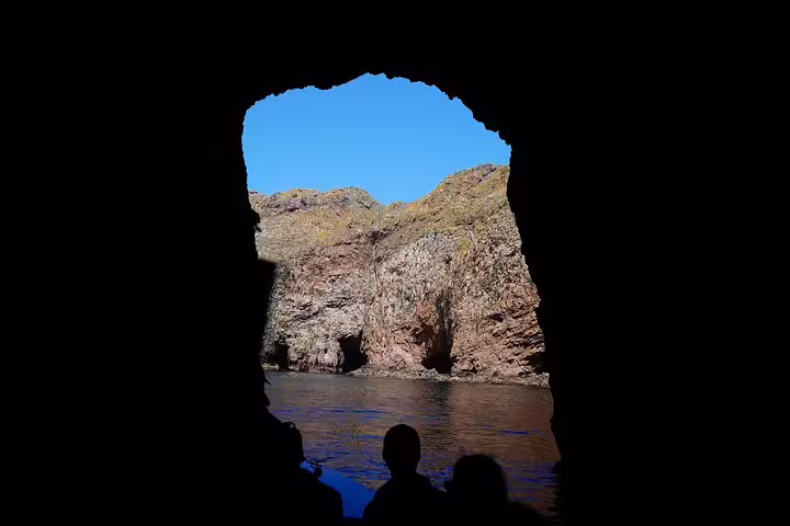 View from a cave on Berlengas Island tour, showcasing rugged cliffs and clear blue skies, perfect for a Lisbon day trip adventure.