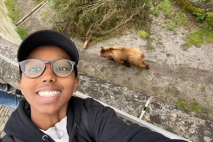 Smiling traveler spots a Bern bear during a self-guided scavenger hunt tour near the Aare River