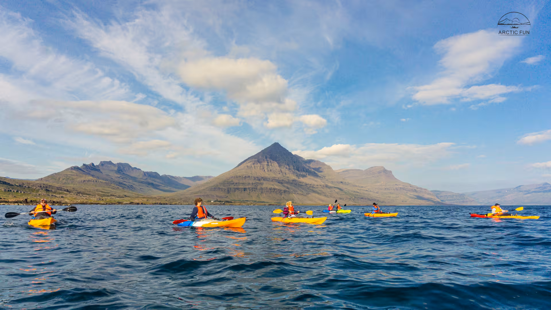 Group kayaking in Berufjörður with stunning mountain views under a clear sky on Iceland's East Fjords.