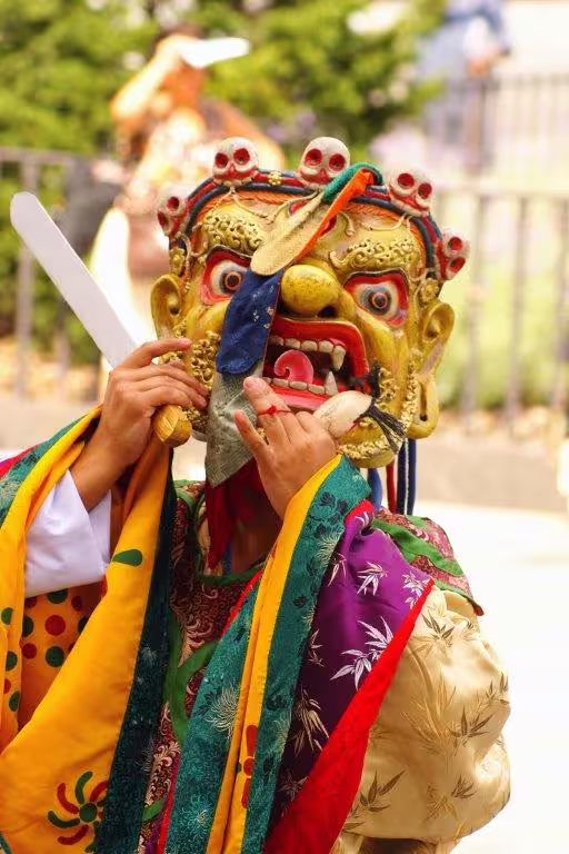 Traditional Bhutanese dancer in ornate mask and colorful attire at a local festival, showcasing cultural heritage.
