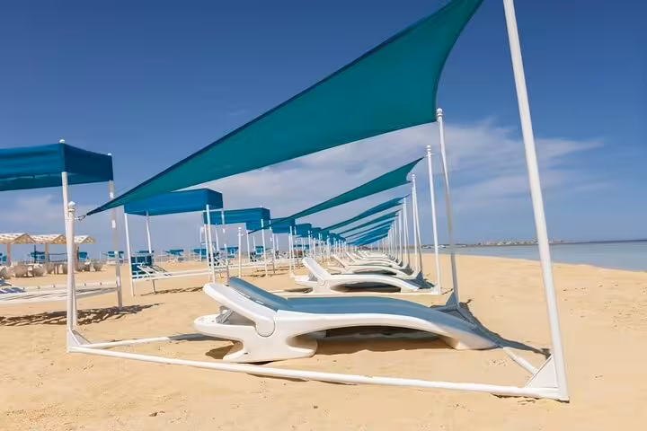 Sun loungers under shade sails on Bianca Island sandy beach, Utopia Island snorkeling tour with transfer from Hurghada