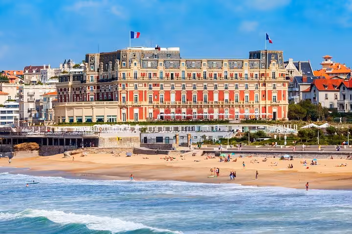Stunning view of Biarritz beach and historic Hôtel du Palais under a vibrant blue sky, perfect for a city tour introduction.