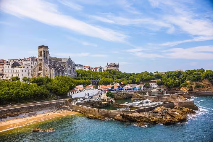 Historic architecture and marina in Biarritz with sandy beaches and vibrant greenery on a sunny day.