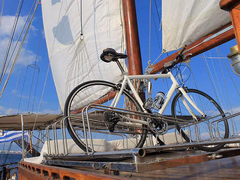 Road bike secured on sailboat deck under white sails, ideal for bike tour with boat sailing adventure