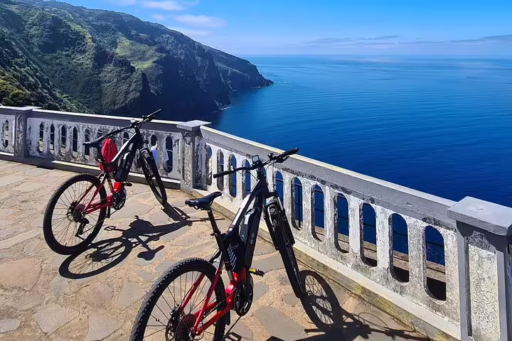 Scenic bike tour on Madeira's west coast featuring two bicycles on a cliffside overlook with stunning ocean views.