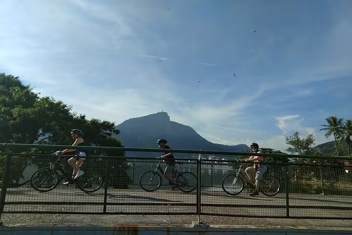 Cyclists ride along a scenic path with Rio's iconic mountain backdrop during a bike tour of beaches and lagoon.