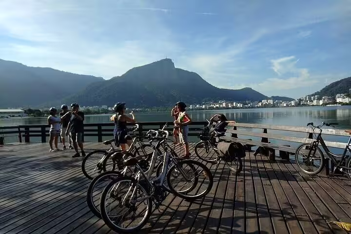Group of cyclists at Rodrigo de Freitas Lagoon, Rio, enjoying panoramic views and tranquil atmosphere on tour.