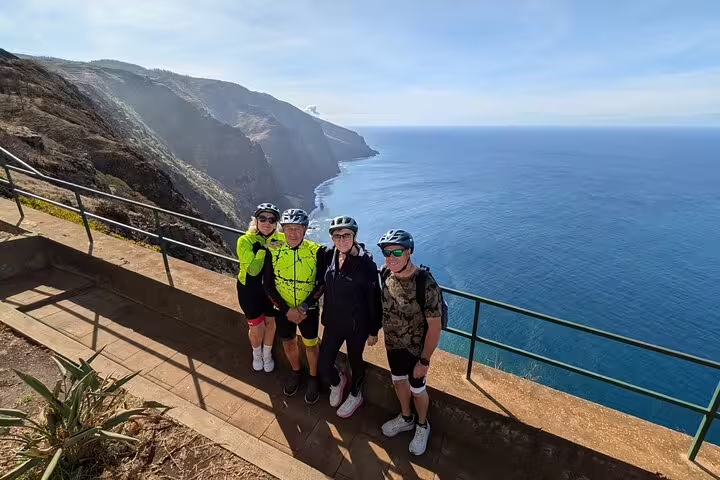 Group of cyclists enjoying a scenic bike tour on Madeira's west coast, overlooking the stunning Atlantic Ocean cliffs.