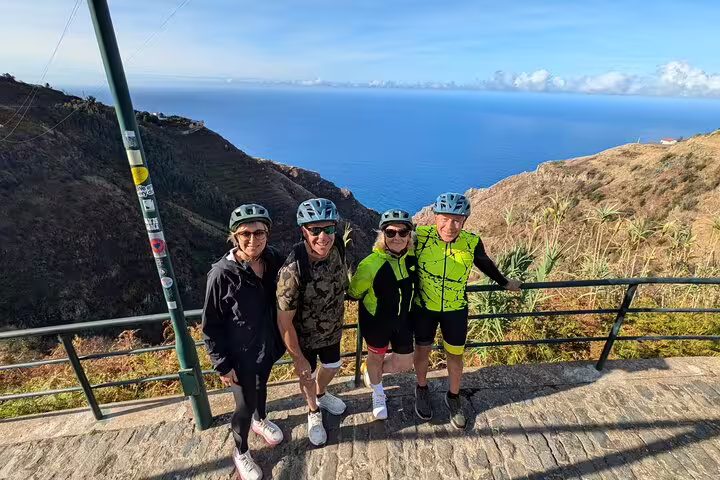Group of cyclists enjoying a scenic bike tour along the stunning west coast of Madeira with ocean views in the background.