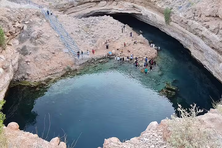 Visitors gather at the breathtaking Bimmah Sinkhole, admiring the turquoise waters and unique geological formations.