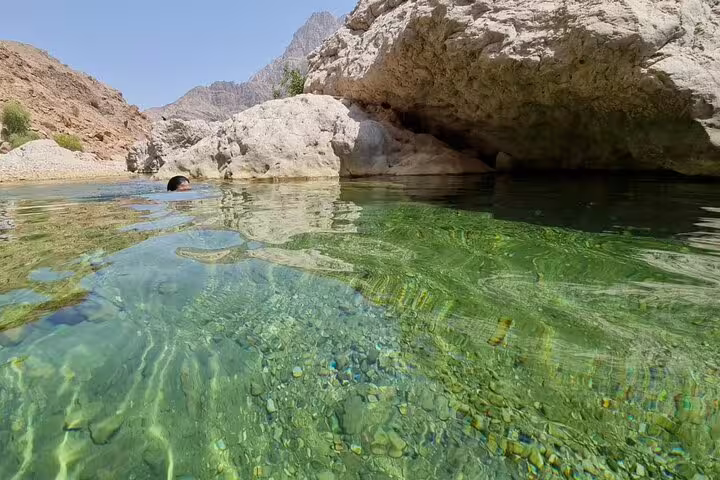 Crystal-clear waters and rocky landscapes invite swimmers at Wadi Al Arbeieen on the Bimmah Sinkhole tour in Oman.