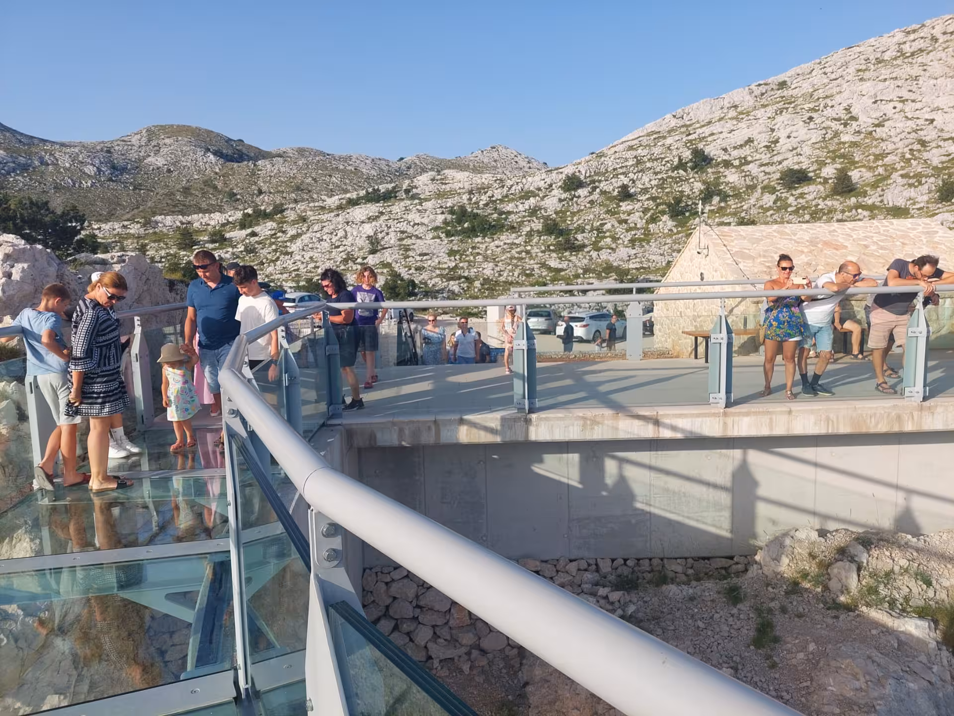 Tourists standing on Biokovo Skywalk glass platform above cliffs, a highlight of Split to Makarska tour