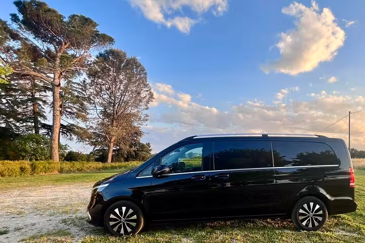 Black luxury van set against a scenic countryside backdrop, perfect for comfortable Milan MXP airport to city transfers.