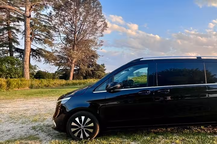 Black Mercedes van parked in a scenic, lush green area, ideal for transfers from Milan to Courchevel.