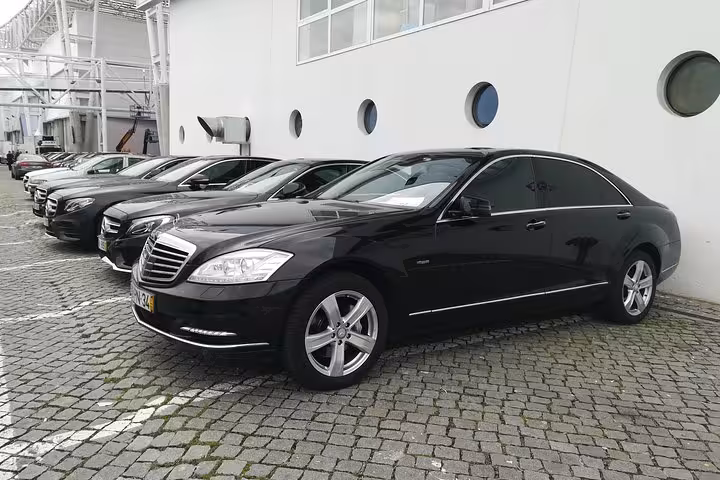 Black executive sedan parked for Lisbon Airport shuttle transfer to Lisbon city center, private pickup service