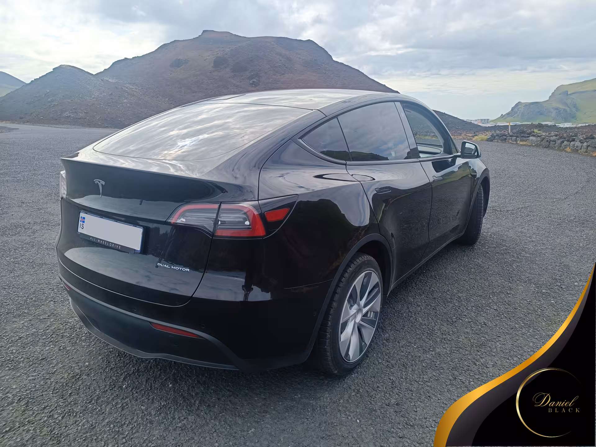 Rear view of black Tesla for private KEF Airport to Reykjavík transfer, parked by Icelandic lava hills