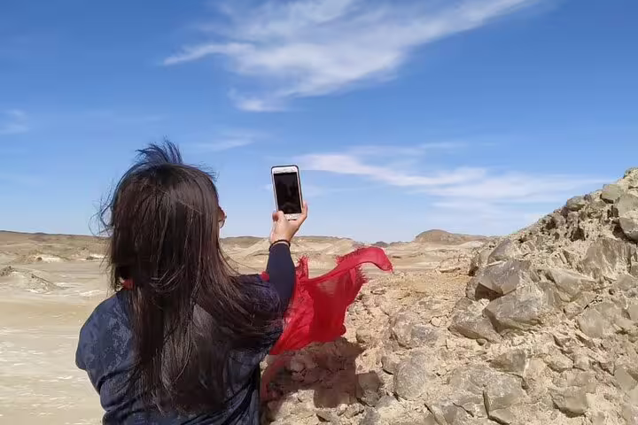 Traveler taking a phone photo at Black Desert viewpoint on 2-day Black & White Desert jeep tour and camp trip