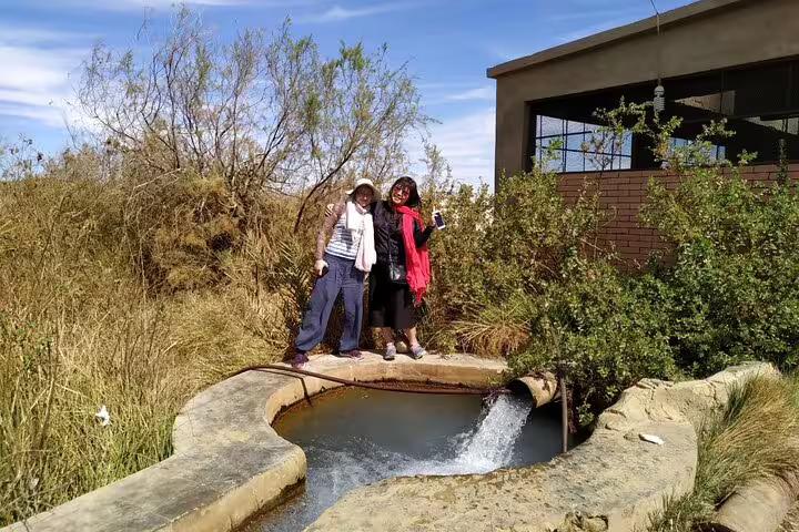 Guests by a desert spring oasis stop during Black & White Desert 2 days adventure tour with jeep and camp