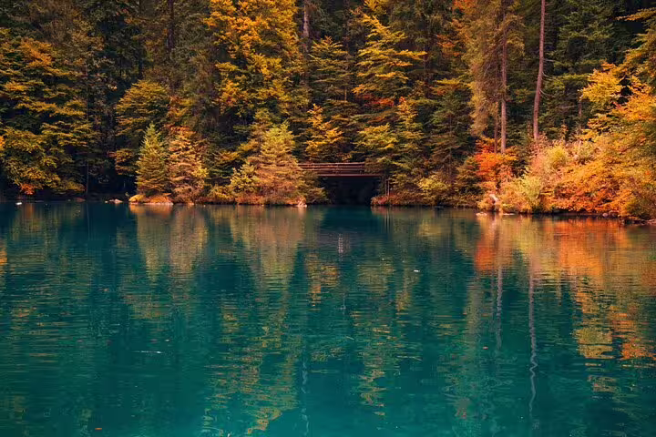 Serene Blausee Lake reflecting vibrant autumn foliage, a highlight of the Interlaken private tour experience.