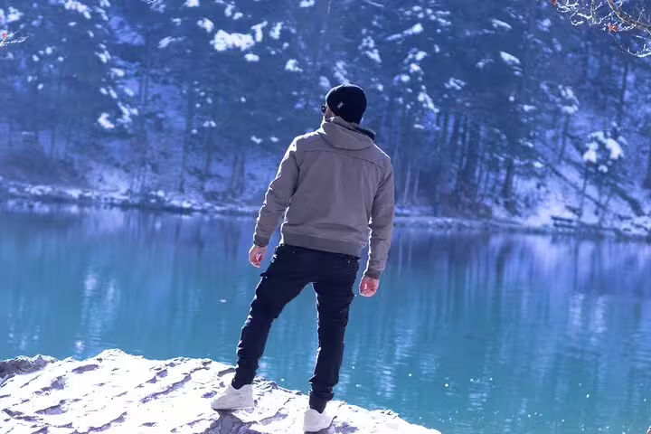 A visitor enjoys the serene winter landscape of Blausee Lake during the Charm of Interlaken Private Tour.