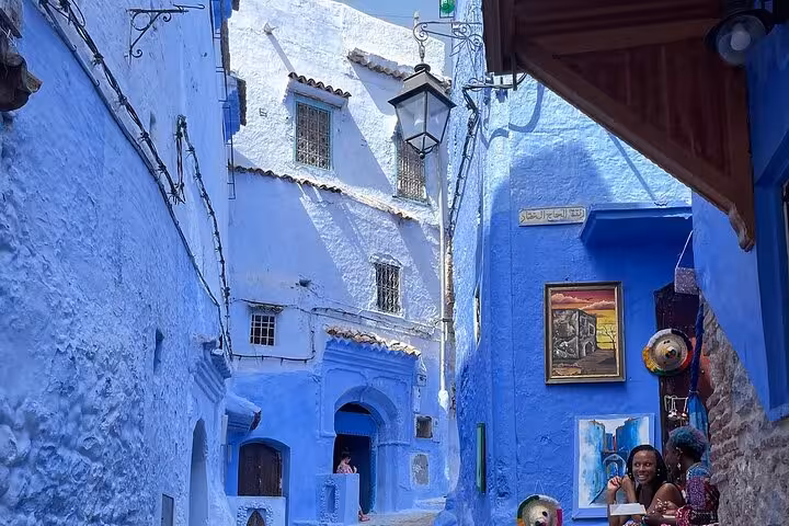 Charming blue alley in Chefchaouen, Morocco, with vibrant street art, perfect for exploring on a guided day tour.