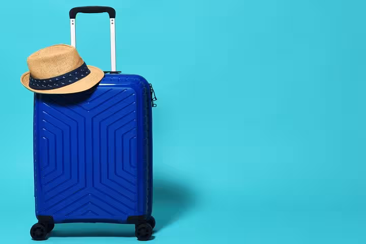 Blue carry-on with straw hat for Amsterdam luggage storage, convenient secure bag drop before canal cruise sightseeing