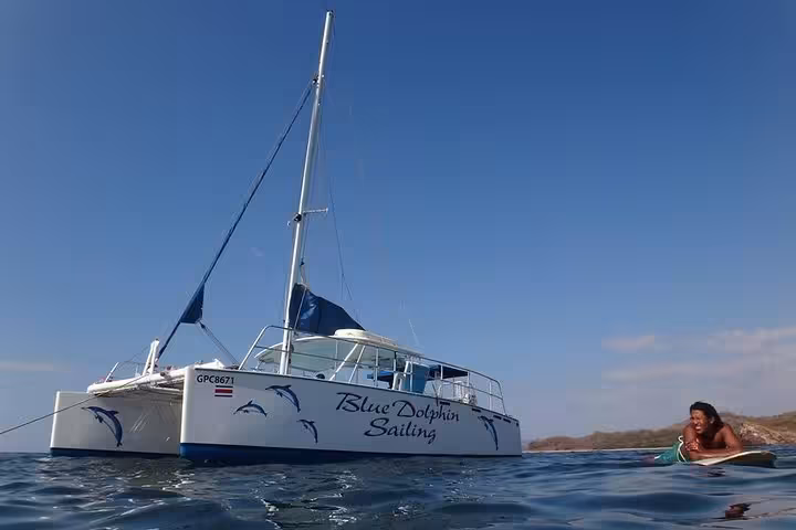 Blue Dolphin Sailing catamaran anchored on calm waters with clear sunny skies overhead.