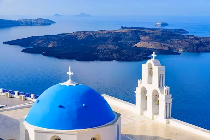 Blue-domed church in Oia overlooking Santorini caldera on private day trip from Crete with transfers
