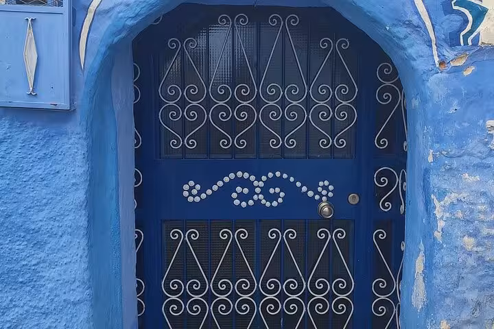 Ornate blue doorway with intricate ironwork in Chefchaouen, a highlight of the guided tour from Fez.