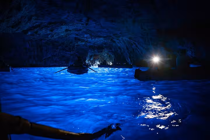 Inside the enchanting Blue Grotto, boats glide over the glowing blue waters, creating a magical atmosphere.