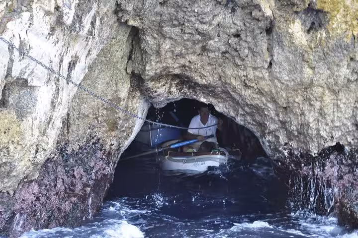 Small boat entering the famous Blue Grotto cave on a scenic Capri tour from Sorrento.