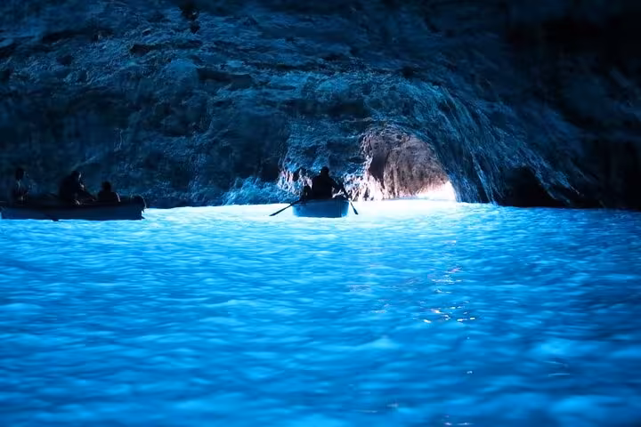 Magical Blue Grotto with glowing azure waters and small boats, a highlight of Capri's half-day boat tour experience.