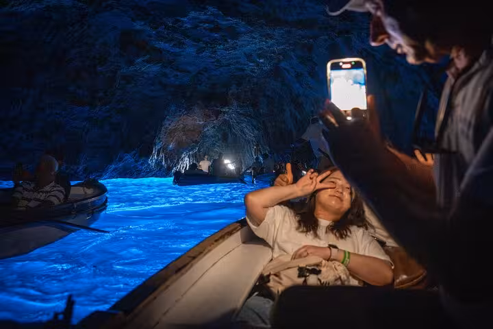 Visitors capture memories inside the mesmerizing Blue Grotto, illuminated by vibrant blue waters, in Capri, Italy.